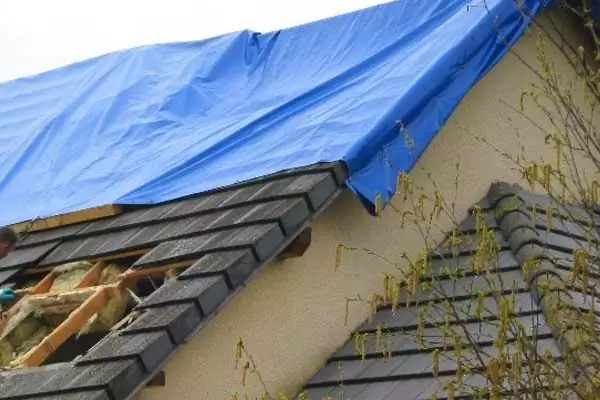 Pose d'une bâche d'urgence sur une toiture endommagée